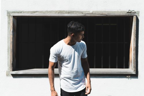 Homme avec un jean et un t-shirt blanc devant un mur