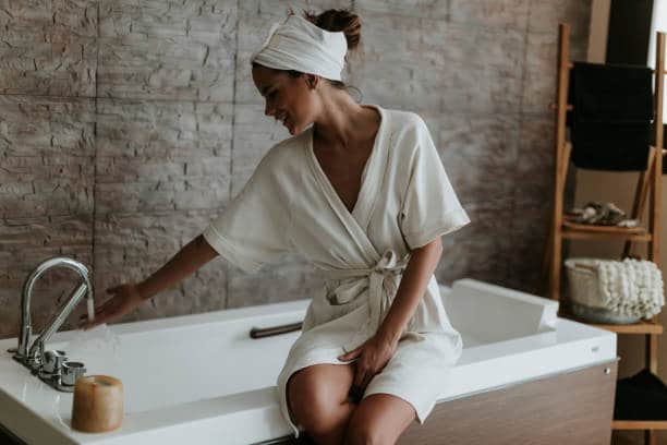 Femme en peignoir blanc qui fait couleur son bain