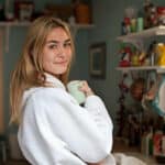 Jeune femme blonde en peignoir qui tient une tasse