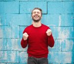 homme souriant qui porte un pull rouge