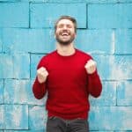 homme souriant qui porte un pull rouge
